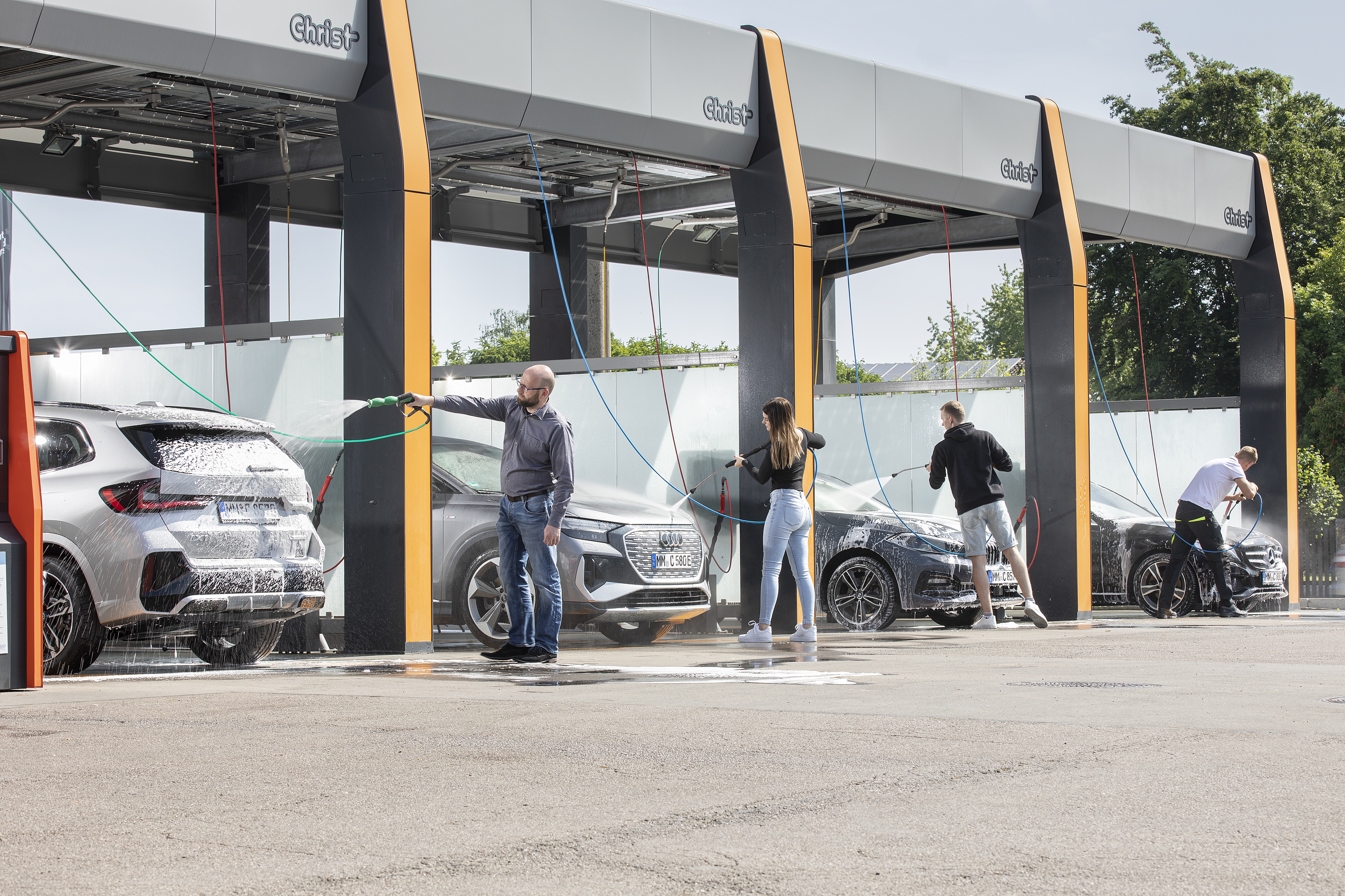 flera personer använder en gör-det-själv biltvätt utomhus.